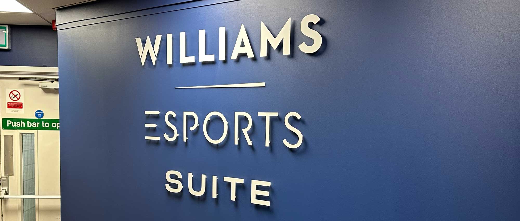 Large format vinyl and acrylic signs designed, printed, and installed for Williams Esports room at Sheffield United Football Club, featuring bold branding graphics and modern esports visuals.